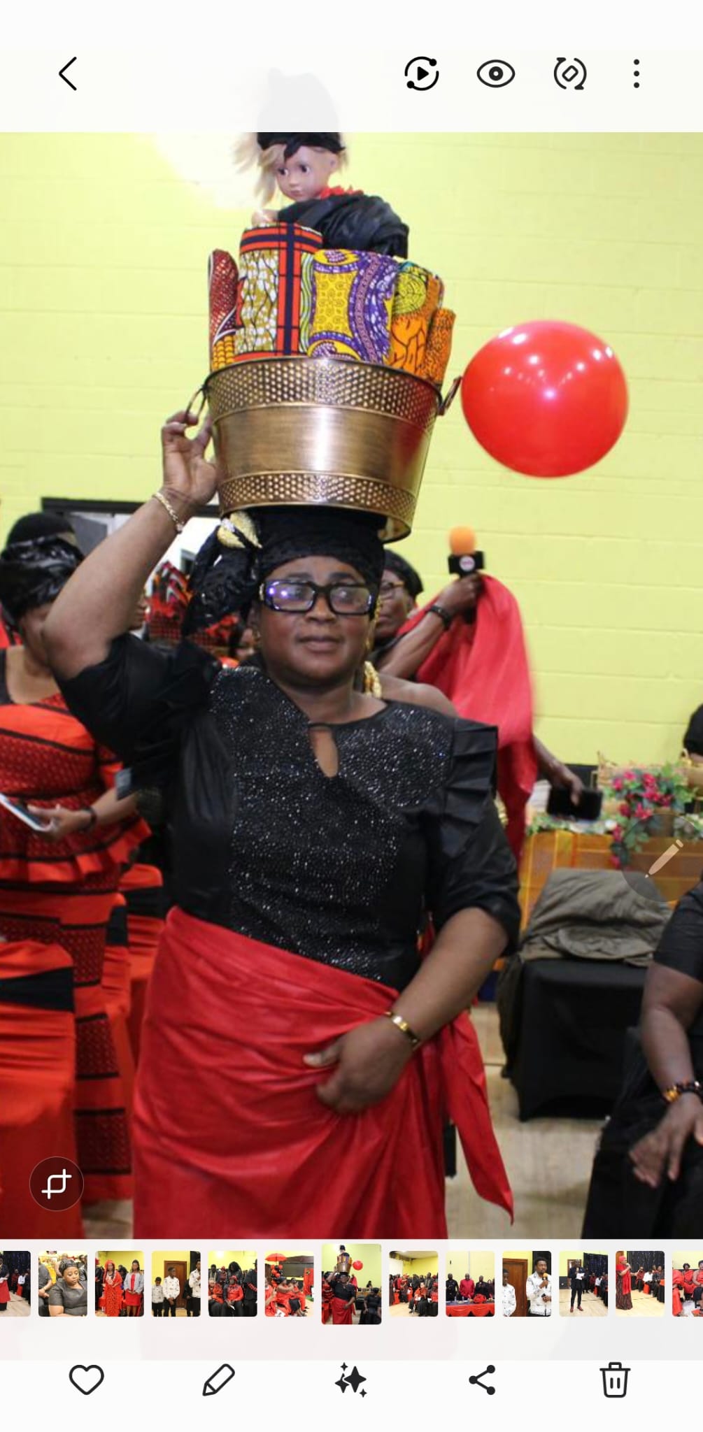 A woman carrying a decorated basket of Ghanaian fabrics during a cultural presentation