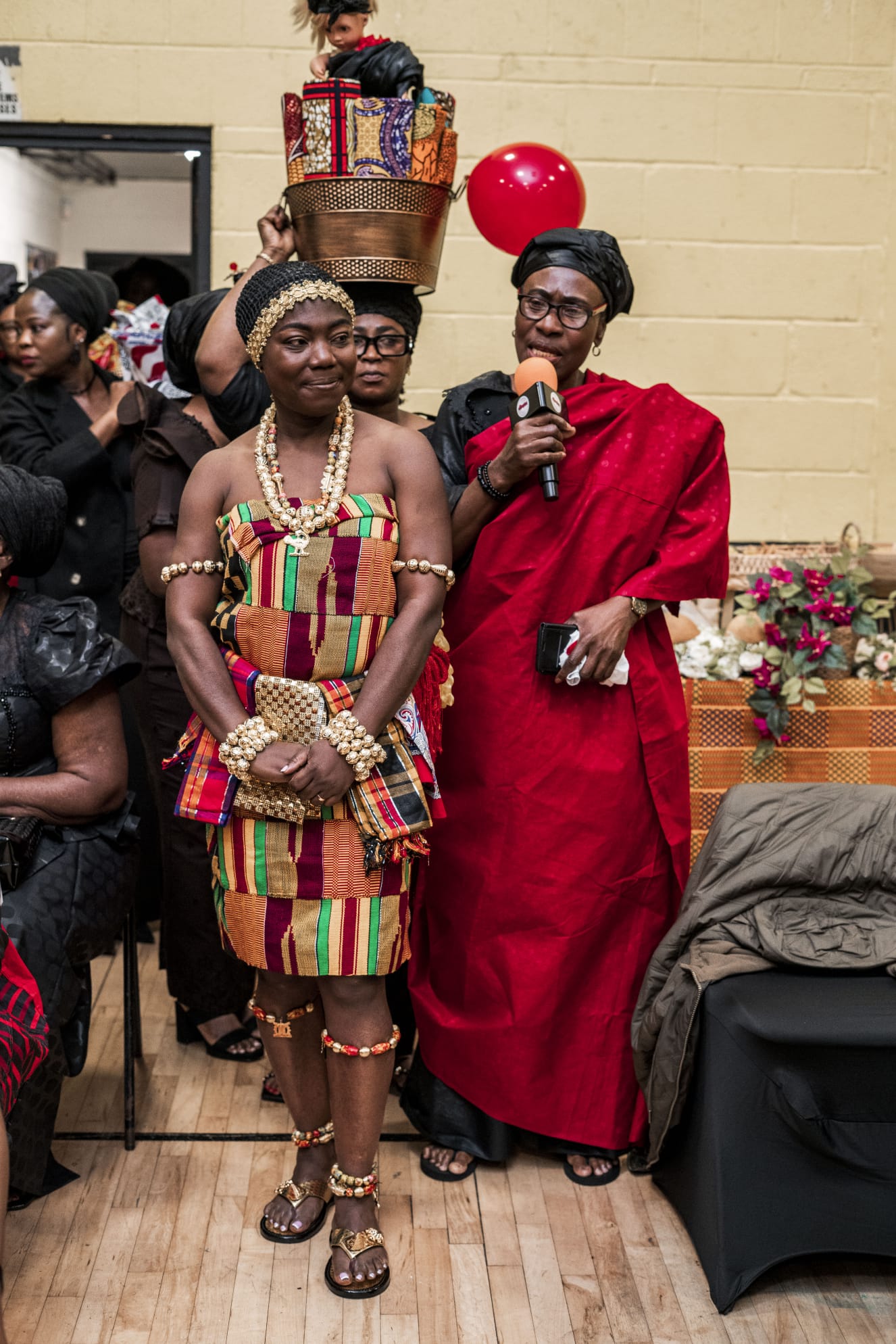 Two women presenting Ghanaian traditional clothing and accessories at an event